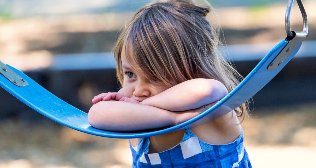 A young girl leaning on a swing