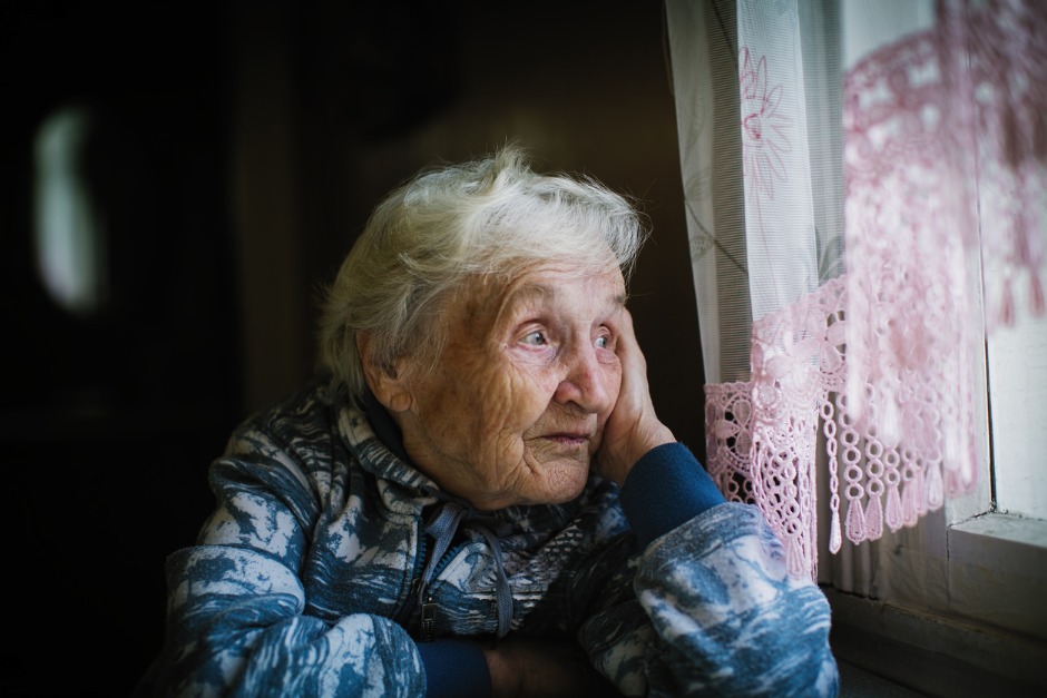 Elderly woman looking out of a window