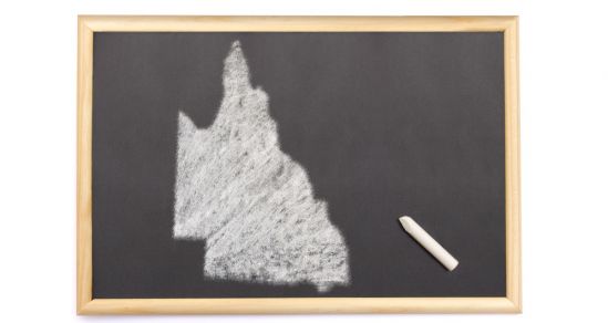 A blackboard with the shape of Queensland state drawn on it. A piece of white chalk lays to the side.