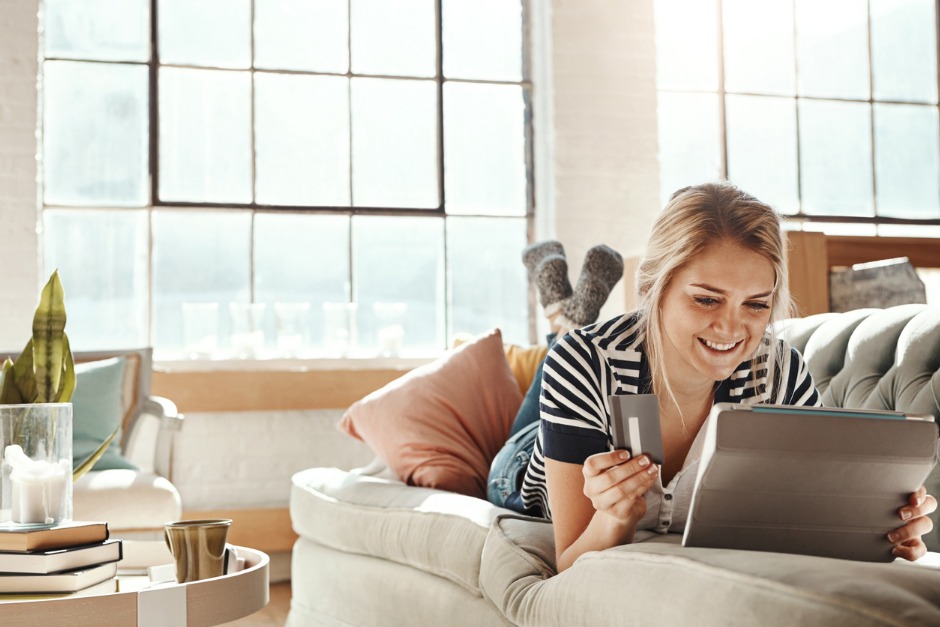 woman shopping online with a credit card and laptop on a couch