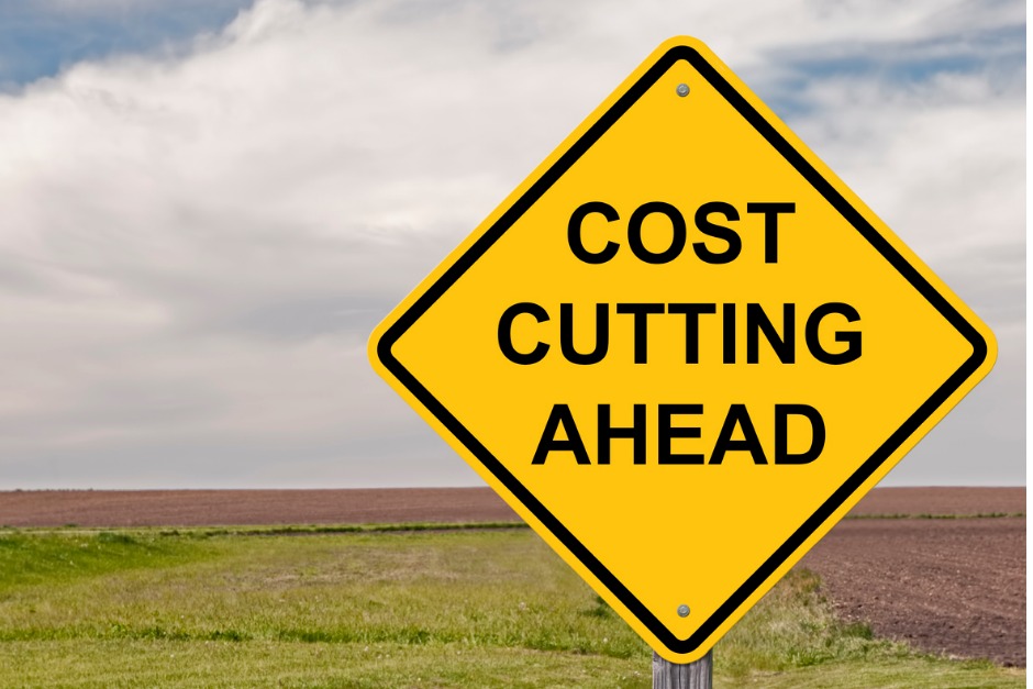 Image of road sign which reads "Cost cutting ahead"