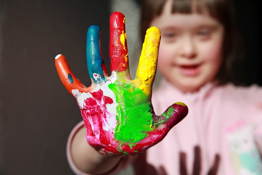 Cute little girl with a painted hand who has Down Syndrome